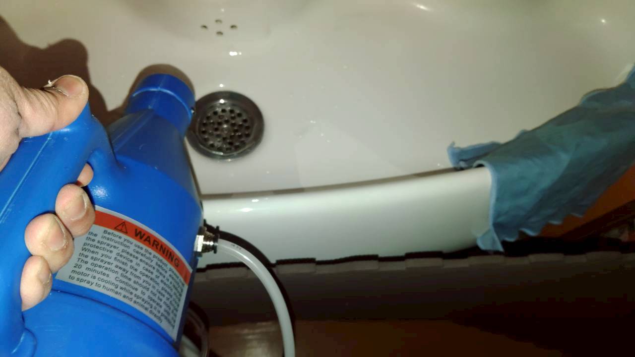 洗面台の下側へ器具を向けた薬剤処理