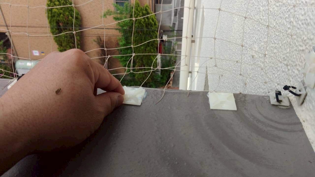 朝霞市の鳩駆除：ベランダの縁で防鳥ネットを留める作業