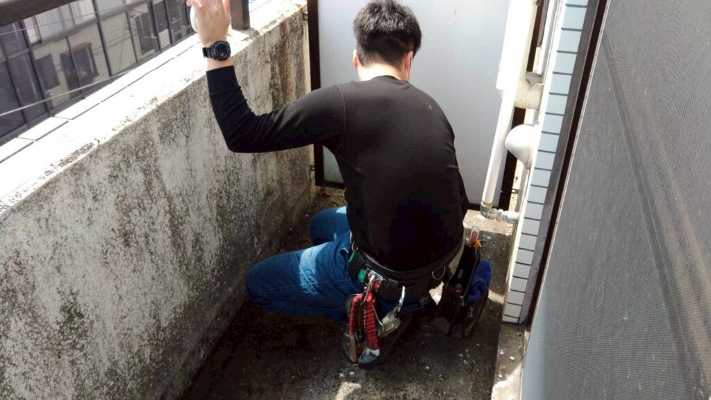 ベランダで鳩対策を行う作業員